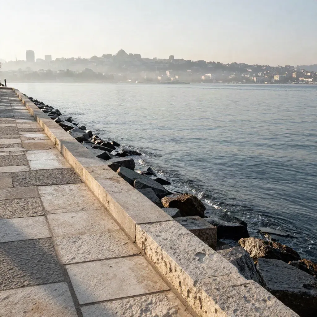 Marmara kıyısı, sisli İstanbul silueti ve sakin deniz, sabah ışığında.